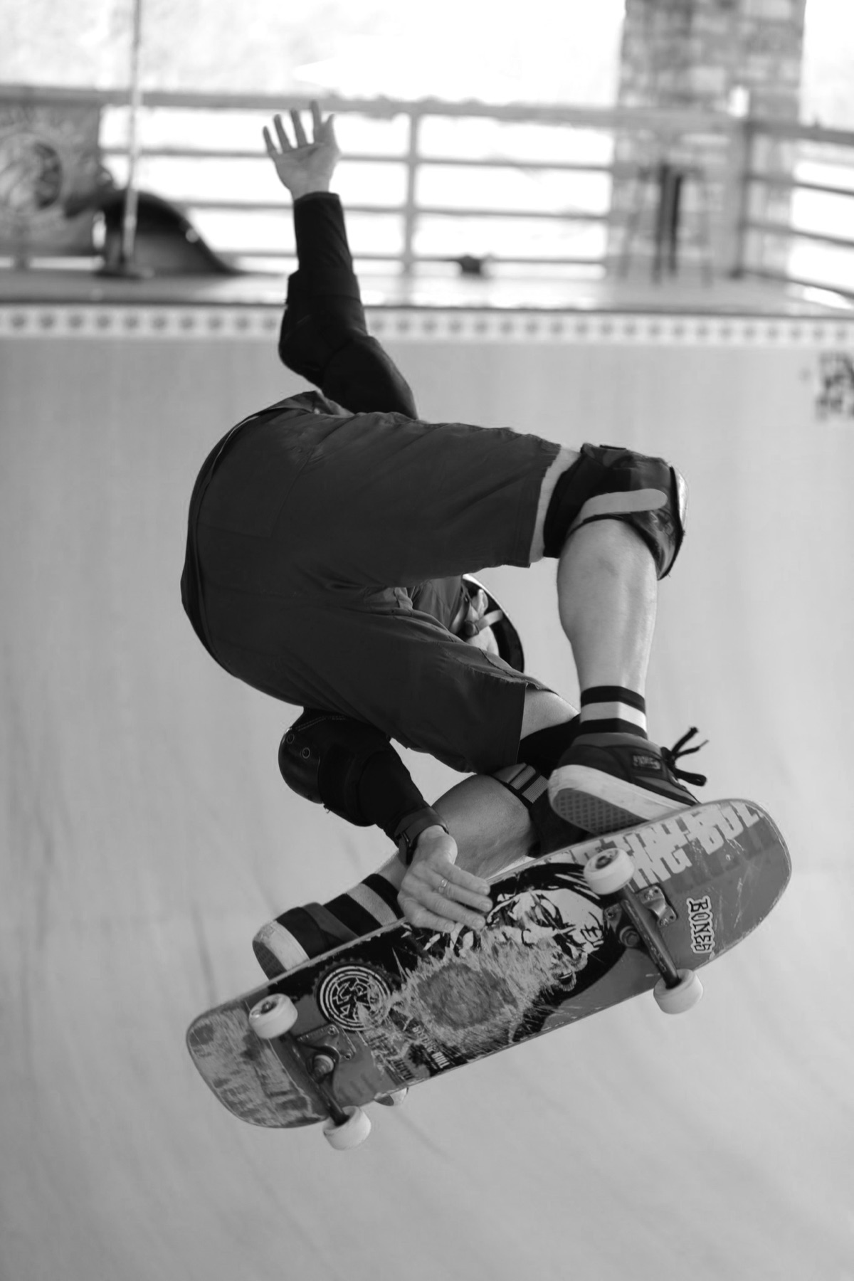 Michael Morrison mid-air on a skateboard ramp, inverted, grabbing the board behind his back leg.